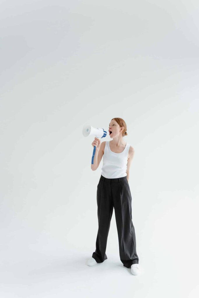 Photo by Tima Miroshnichenko: https://www.pexels.com/photo/a-woman-in-white-tank-top-and-black-pants-holding-a-megaphone-7202787/